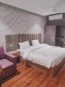 勒克瑙Hotel Sharma Regency的一间卧室配有一张大床和一张紫色椅子