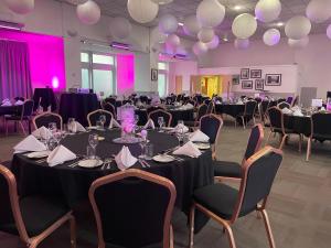 曼彻斯特钟摆酒店 的宴会厅配有圆桌和椅子,拥有紫色灯光