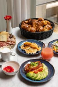 卢森堡Hotel Le Place d'Armes - Relais & Châteaux的餐桌,盘子和一篮面包