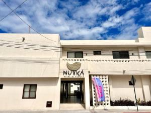德尔奇亚港Nuxká Hotel by Heaven的白色的建筑,上面有尼卡标志
