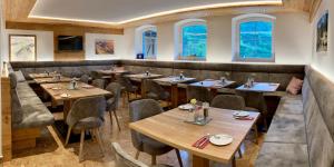 上陶恩温伯格酒店的餐厅设有木桌、椅子和窗户。