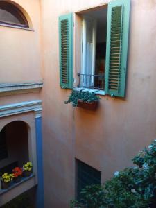 斯佩洛Casa di Emanuela的一座带绿色百叶窗的建筑和一个带鲜花的阳台