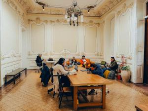 利马Viajero Kokopelli Lima - Barranco Hostel的一群人坐在一个房间里桌子旁