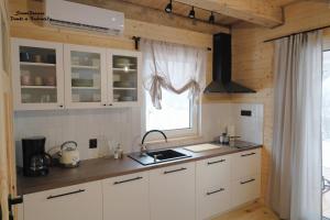 比亚沃维耶扎SzumiPuszcza - domki, sauna, jacuzzi的厨房配有白色橱柜和窗户。
