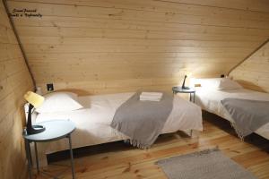 比亚沃维耶扎SzumiPuszcza - domki, sauna, jacuzzi的木墙客房的两张床