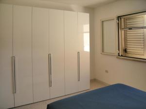 托雷瓦多Villa Giulia Salento Mare的卧室配有白色橱柜和窗户。