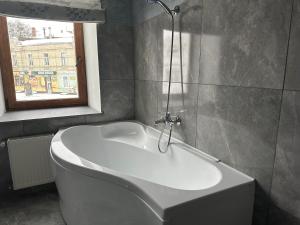 波尔塔瓦Centralnyi hotel的带窗户的浴室内的白色浴缸