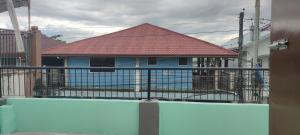 奥隆阿波Baloy beach house的围栏后面有红色屋顶的房子