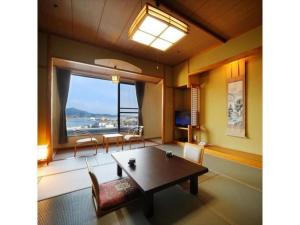 气仙沼市Sun Marine Kesennuma Hotel Kanyo - Vacation STAY 21044v的客厅设有桌子和大窗户