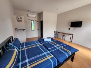 Ban Khao Khayai (1)เช็คอินรีสอร์ท ชัยนาท的一间卧室配有一张带蓝色床单的床和一台平面电视。
