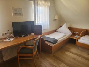 Zuzenhausen达赫森弗兰茨酿酒厂旅馆的酒店客房配有一张桌子、一张床和一台电视
