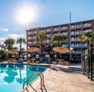加尔维斯敦Quality Inn & Suites Galveston - Beachfront的大楼前的游泳池配有椅子和遮阳伞