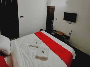 新德里OYO Kings Court的卧室配有红色和白色的床,提供毛巾