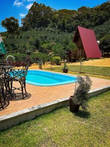上大瓦尔任Chalé de Madeira em Vargem Alta的一个带桌子和长凳的游泳池以及一座房子