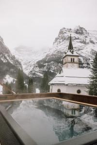 格林德尔瓦尔德Hotel Fiescherblick的享有教堂和雪覆盖的山脉的景色