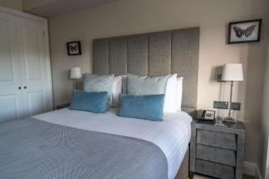 威布里治欧特兰德公园酒店的一间卧室配有一张大床和两个蓝色枕头