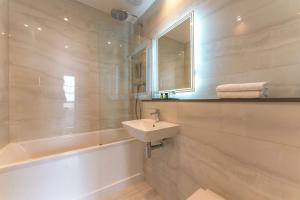 威布里治欧特兰德公园酒店的一间带水槽、浴缸和镜子的浴室