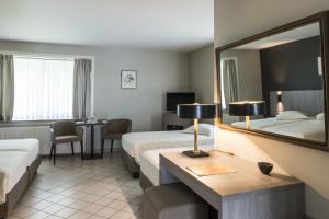 萌纳姆登邦滕奥斯酒店的酒店客房,设有两张床和镜子
