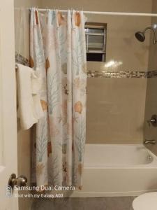Long Bay HillsVilla Victoria Pool Retreat的浴室配有淋浴帘和浴缸。