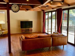 镰仓市極楽寺邸 - Gokurakuji House的客厅配有沙发和墙上的时钟