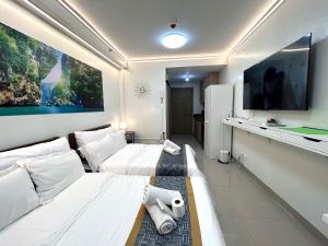 马尼拉Shore Residences MOA Dynastel Staycation的酒店客房设有两张床和一台平面电视。