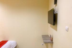 当格浪RedDoorz @ Balaraja Centre Plaza的卧室配有一张床,墙上配有电视。