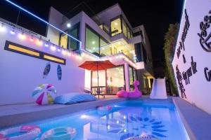 南芭堤雅Pupae Pool Villa Pattaya的一座带遮阳伞的游泳池的房子