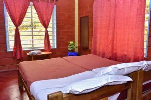 马迪凯里Eshwari Cottage的一间卧室配有一张带红色窗帘的床和一扇窗户