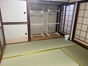 Sukumoゲストハウス アルベルゲ Guesthouse ALBERGUE SAKURA的一间设有两扇玻璃门的房间和一间设有地板的房间