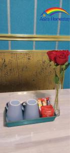 哥打巴鲁AAIRA Troika Residence,Kota Bharu的盘子上放两个杯子,花瓶上放玫瑰