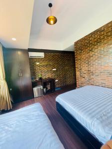 顺化Mandarin Homestay Hue的一间卧室设有两张床和砖墙