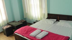 西姆拉Lakshay Regency的一间卧室配有一张床铺,床上铺有红色毯子