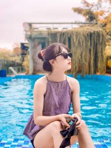 巴位Ba Vì Madela的坐在游泳池旁的太阳镜里的女人