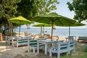 佩母德兰塔曼沙丽巴厘Spa度假酒店的海滩上一组桌椅和遮阳伞