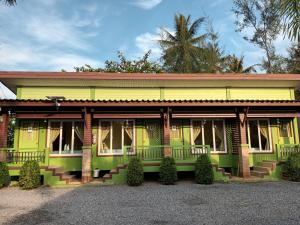 Ban Pak Ba RaKrajomsai Resort เจ้าของมุสลิมห้ามดื่มแอลกอฮอล์的黄色和绿色的房子,后面有棕榈树