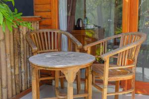 珀尼达岛Bhavana Cottage的门廊上的一张木桌和两把椅子