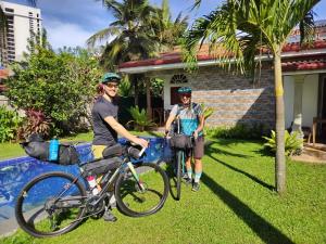 尼甘布Ocean Gate Negombo的两个人站在房子前面,骑着自行车