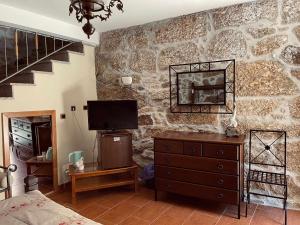 Aldeia Viçosa金塔多米奥旅馆的一间卧室设有石墙、电视和梳妆台
