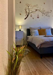 兰讷斯Dejlig 2 værelses lejlighed的卧室配有一张床铺,墙上挂着一棵树