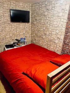 佩鲁日La chambre des secrets Perougien的一间卧室设有一张红色的床,石墙上配有电视