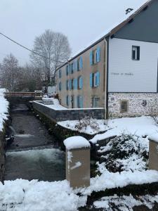 比桑Gîte Au Creux Du Moulin的河边的地面上积雪的建筑物