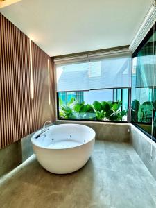 拉差汶里Rock Resort Ratchaburi的大型窗户客房内的白色大浴缸