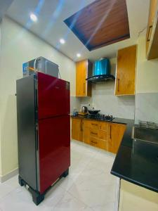 拉合尔Luxury Apartment in Bahria Town, Lahore的厨房配有红色冰箱和木制橱柜