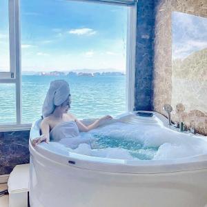 下龙湾Aquamarine Premium Cruise的浴缸里的一个女人,有窗
