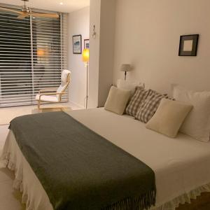 萨洛Apartamento sobre el mar的卧室配有一张白色大床和椅子