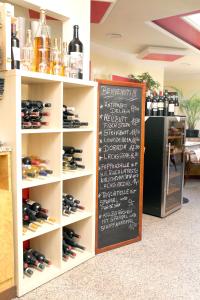 Eilenburg艾斯咖啡馆-比萨店里亚托酒店的装有瓶装葡萄酒和黑板的架子