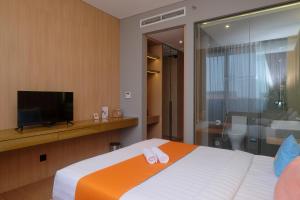DemanganSans Hotel RG Living Jogja by RedDoorz的酒店客房,配有床和电视