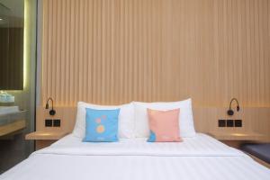 DemanganSans Hotel RG Living Jogja by RedDoorz的床上有三个枕头