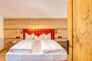 洛伊塔施奥瑟尔施奈德公寓的一间卧室配有一张带红色床头板和白色枕头的床。