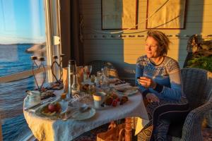吕瑟希尔Strandflickornas Husen invid Havet的坐在餐桌上吃一盘食物的女人
